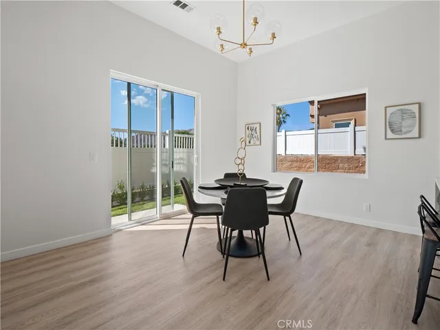 a dining room with wooden floor a chandelier a glass table and chairs