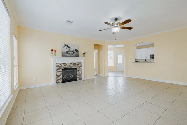 a view of a livingroom with a fireplace a ceiling fan and windows