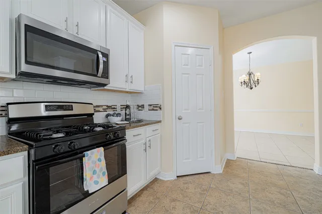 a kitchen with stainless steel appliances granite countertop white cabinets and black stove top oven with granite countertops