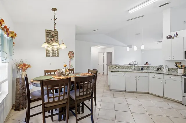 a kitchen with a dining table chairs and white cabinets