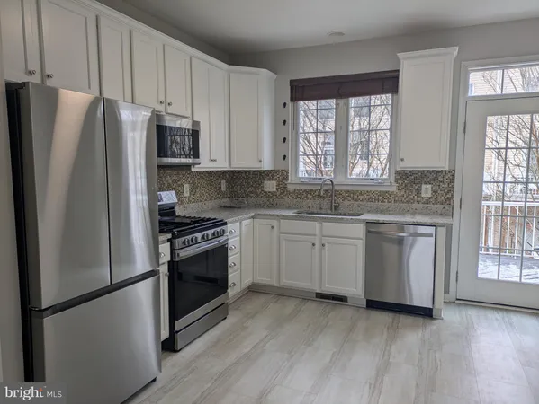 a kitchen with granite countertop a refrigerator and a stove top oven