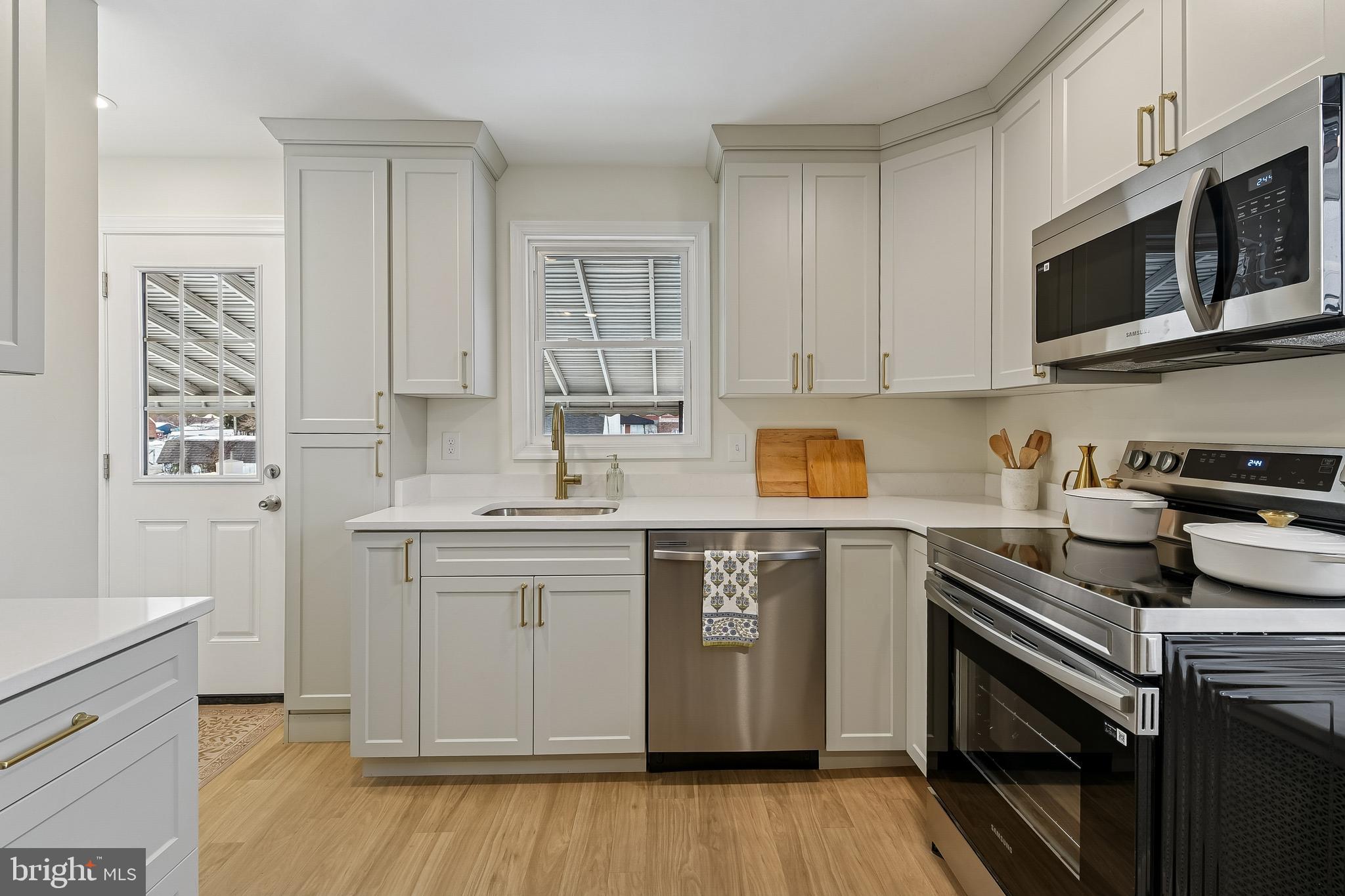 100 Margaret Avenue Baltimore, MD 21221 - Photo 8 of 44 a kitchen with stainless steel appliances granite countertop a stove a sink dishwasher and a microwave oven with wooden floor