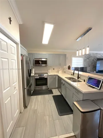 a kitchen with a sink dishwasher stove and white cabinets with wooden floor