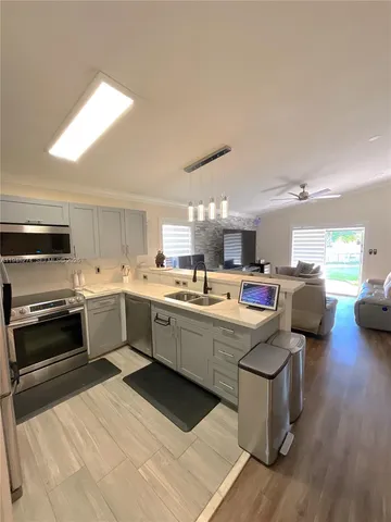 a view of a kitchen with a sink and dishwasher a stove top oven with wooden floor