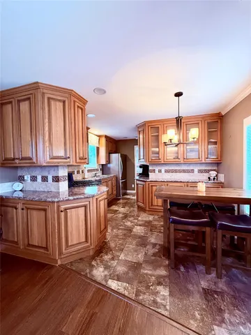 a kitchen with stainless steel appliances granite countertop a stove a sink dishwasher and a refrigerator with wooden cabinets