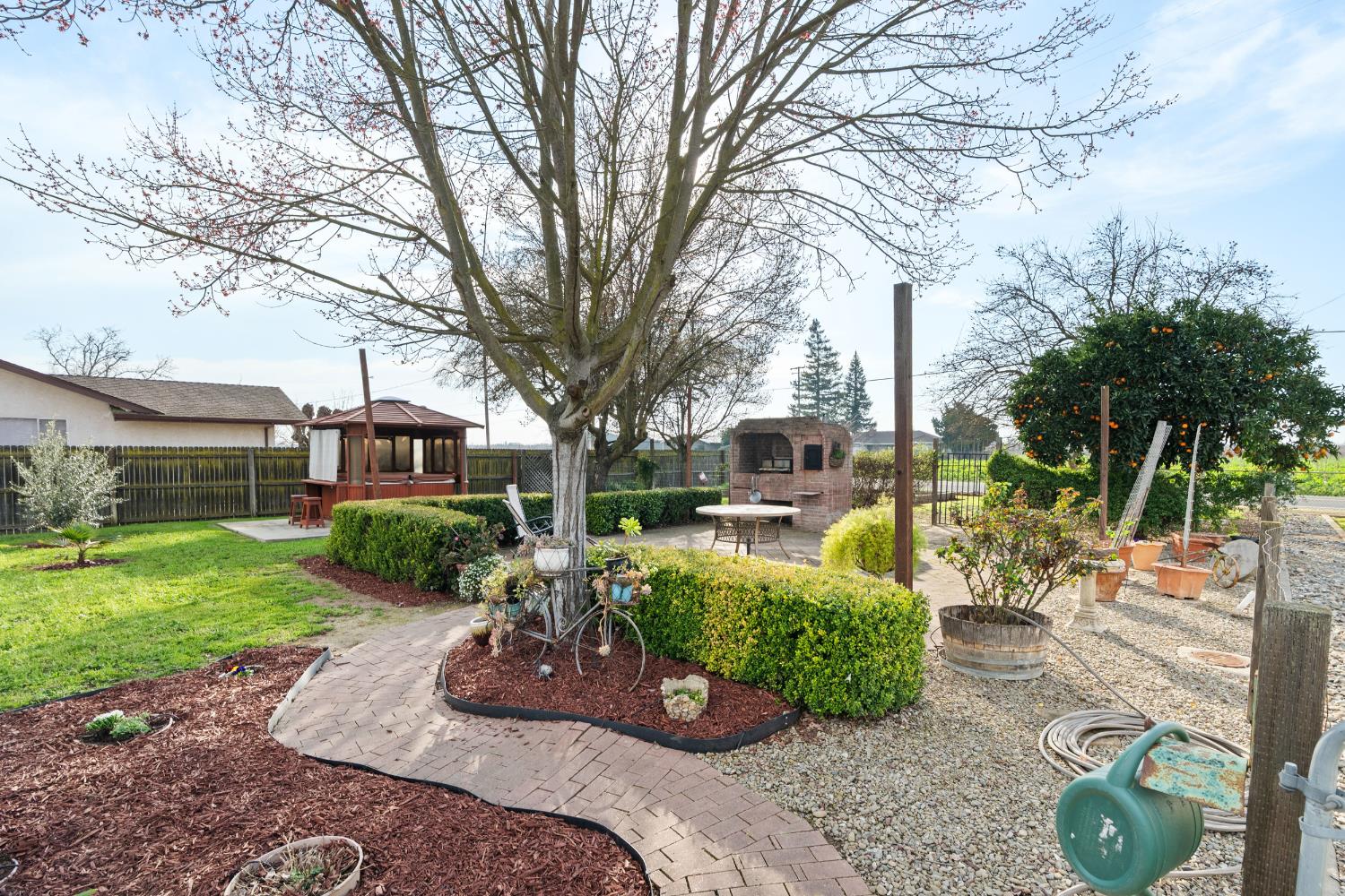 5610 North Confer Road Stockton, CA 95215 - Photo 17 of 40 Clockwise from Left: landscaped yard, hot tub with TV stand, brick patio, brick oven and rotisserie, garden with irrigation, private fruit trees.