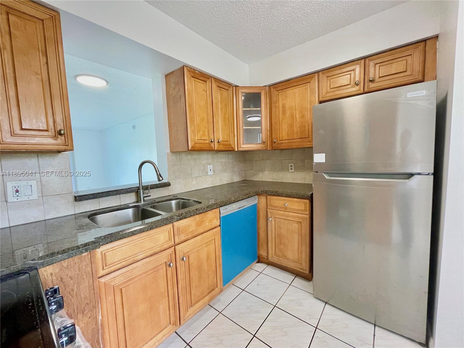 2209 South Cypress Bend Drive, Unit 407 Pompano Beach, FL 33069 - Photo 6 of 53 a kitchen with stainless steel appliances granite countertop a refrigerator and a sink
