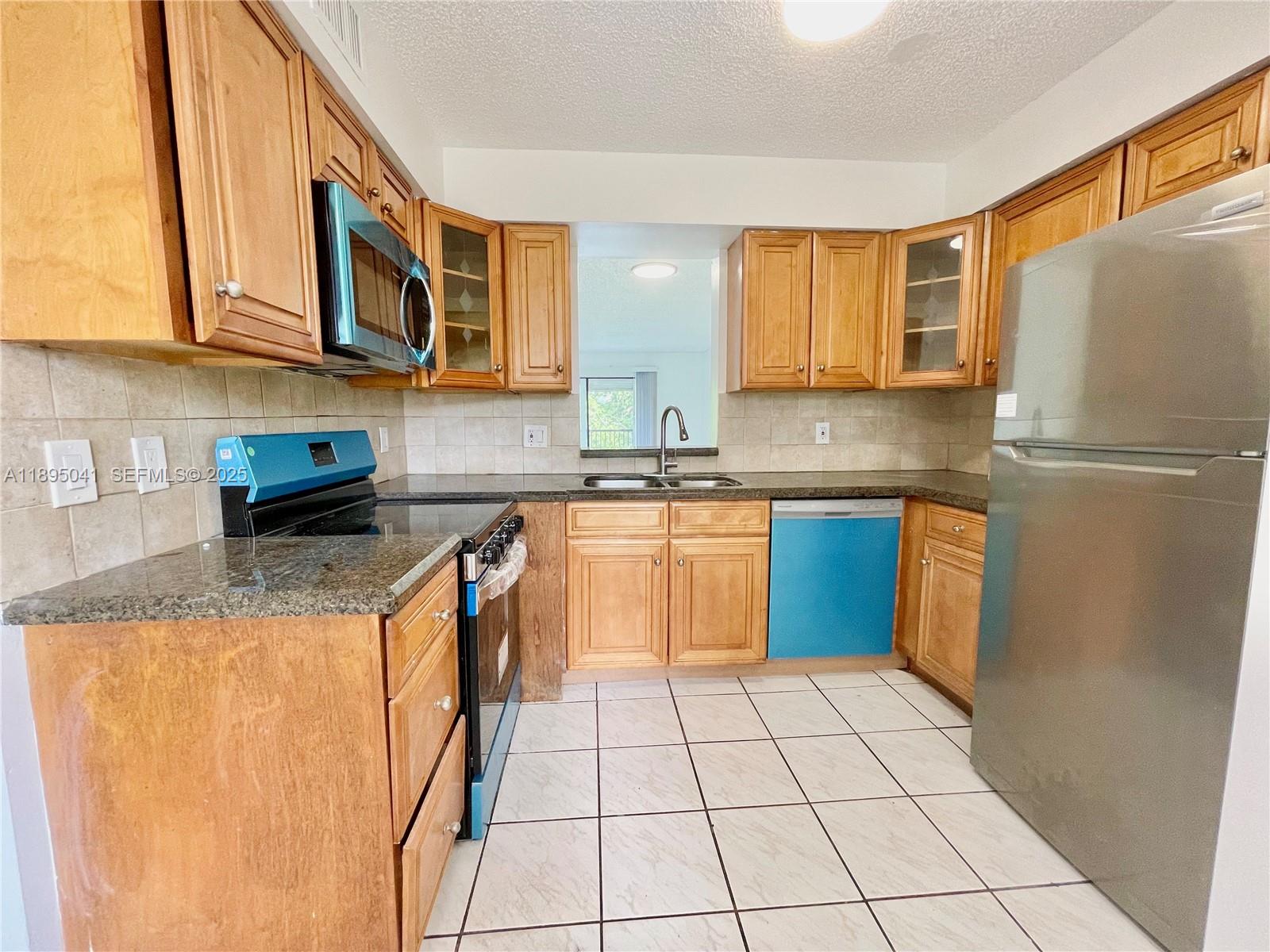 2209 South Cypress Bend Drive, Unit 407 Pompano Beach, FL 33069 - Photo 8 of 53 a kitchen with stainless steel appliances granite countertop a stove a sink dishwasher and a refrigerator