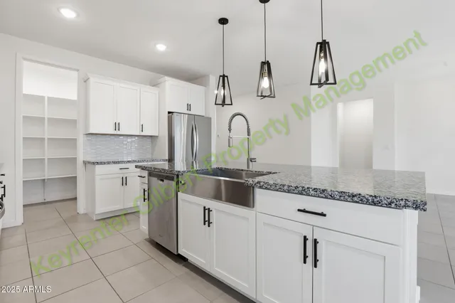 a large white kitchen with a sink a window and stainless steel appliances
