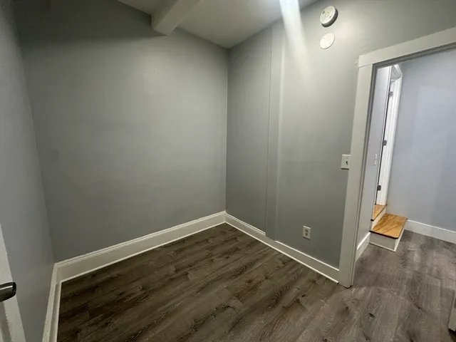 an empty room with wooden floor and entrance