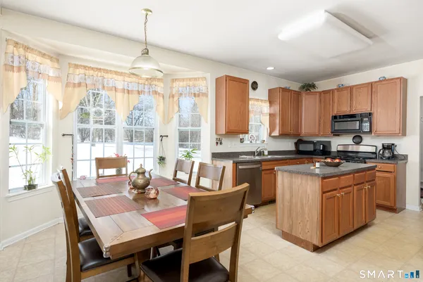 a kitchen with stainless steel appliances granite countertop a stove top oven a sink dishwasher a dining table and chairs with wooden floor