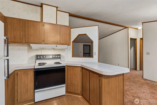 a kitchen with stainless steel appliances granite countertop a refrigerator a stove and a sink with wooden floor