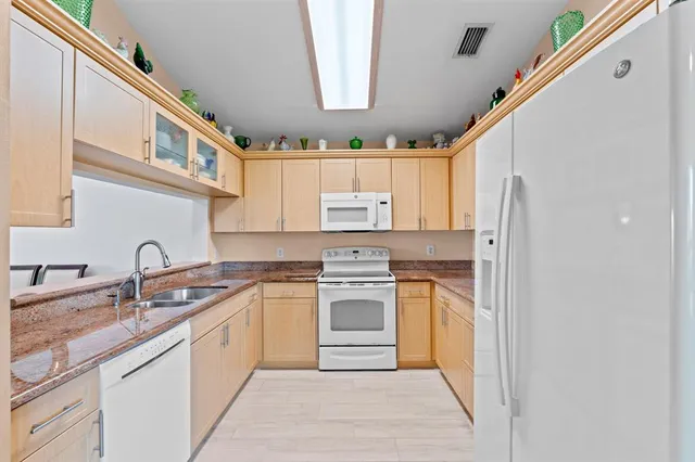 a kitchen with granite countertop a sink stainless steel appliances and white cabinets