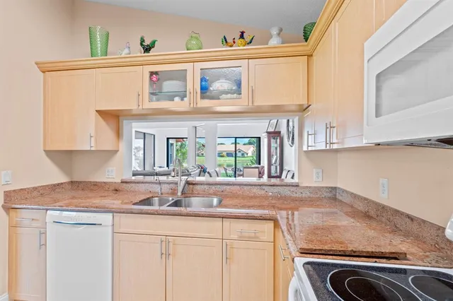 a kitchen with granite countertop a refrigerator a sink and white cabinets