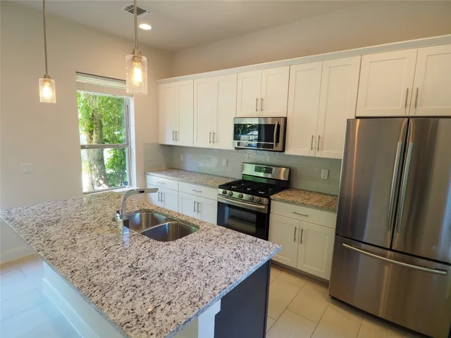 a kitchen with kitchen island a sink a stove a refrigerator and microwave