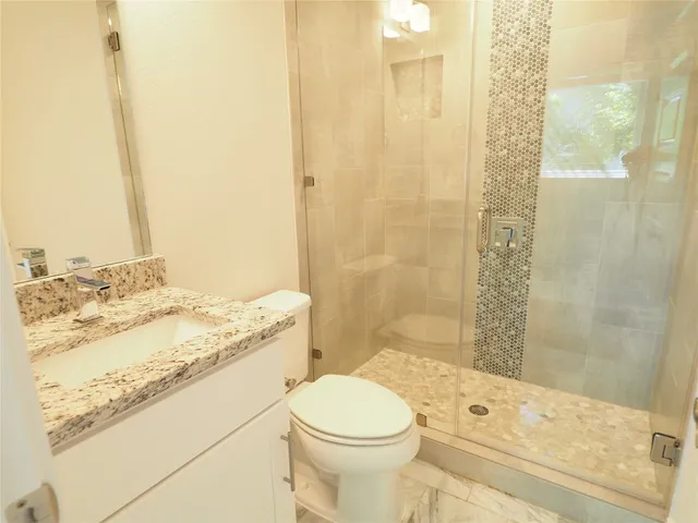 a bathroom with a granite countertop toilet sink and mirror