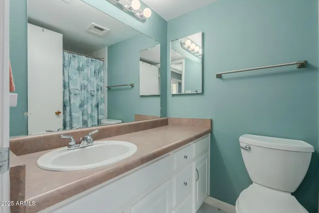 a bed sitting in a bedroom next to a window and a chandelier