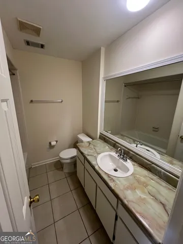 a bathroom with a granite countertop sink a toilet and a mirror