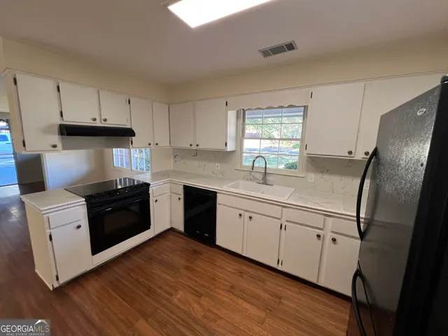 a kitchen with stainless steel appliances a refrigerator sink and wooden floor