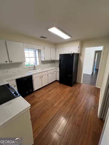 a kitchen with granite countertop a refrigerator a sink dishwasher and wooden cabinets