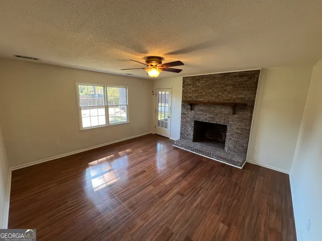 an empty room with wooden floor fireplace and a window