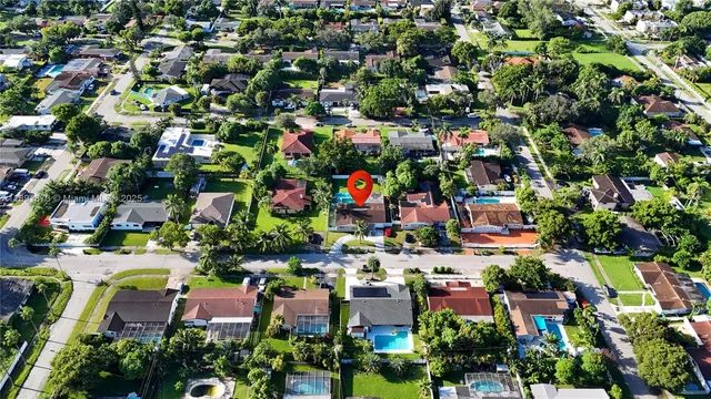 an aerial view of residential houses with outdoor space and trees