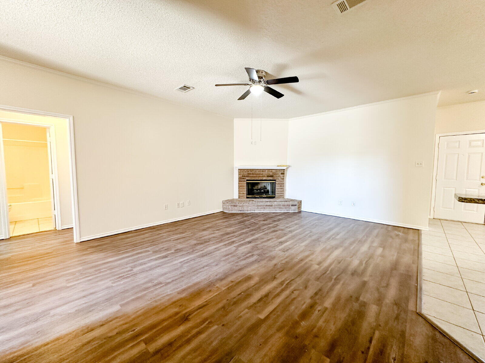 10622 Boston Avenue Lubbock, TX 79423 - Photo 5 of 28 an empty room with wooden floor a ceiling fan and windows