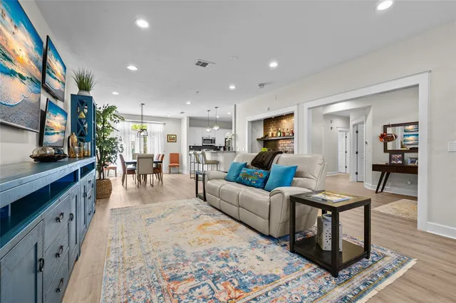 a living room with furniture and a dining table with wooden floor