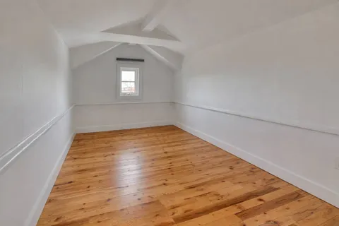 a view of a hallway with wooden floor and a window