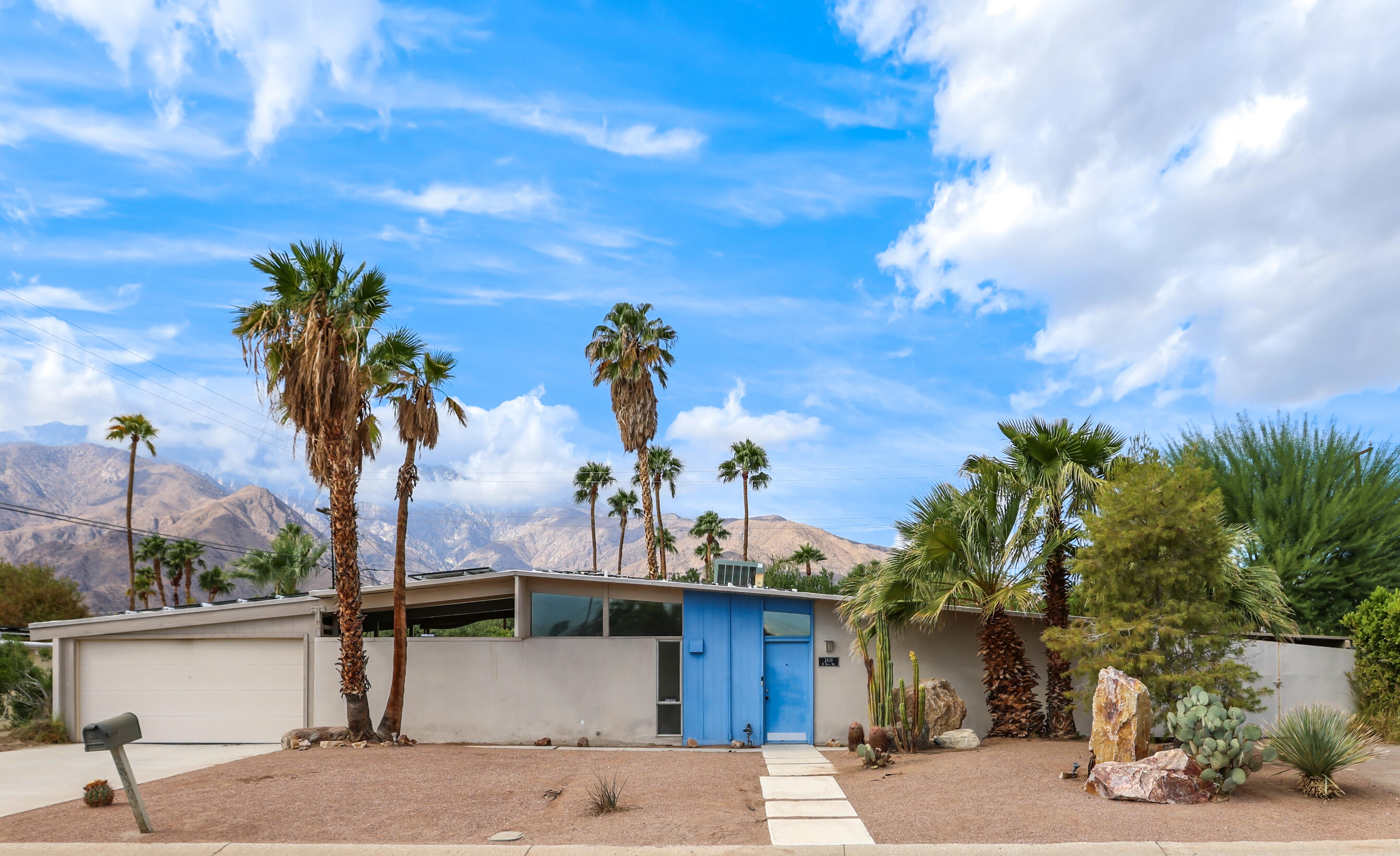 a front view of a house with garden and trees