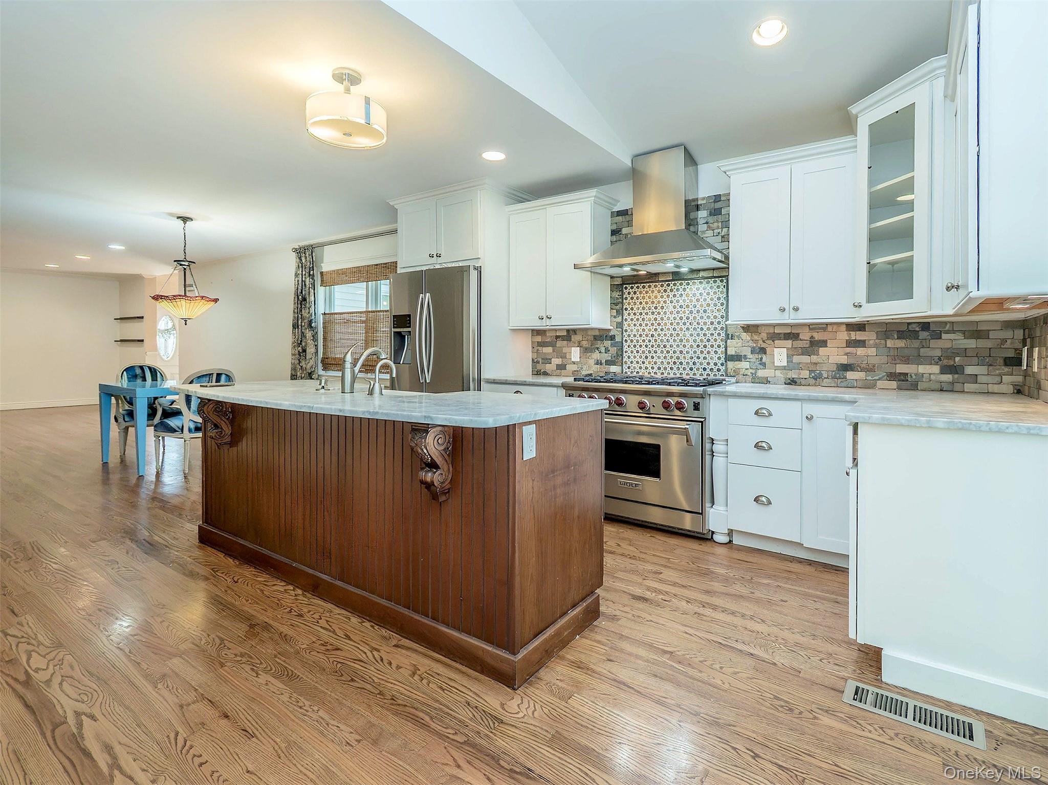 21 Marwood Road North Port Washington, NY 11050 - Photo 9 of 35 a kitchen with kitchen island granite countertop a sink cabinets and wooden floor