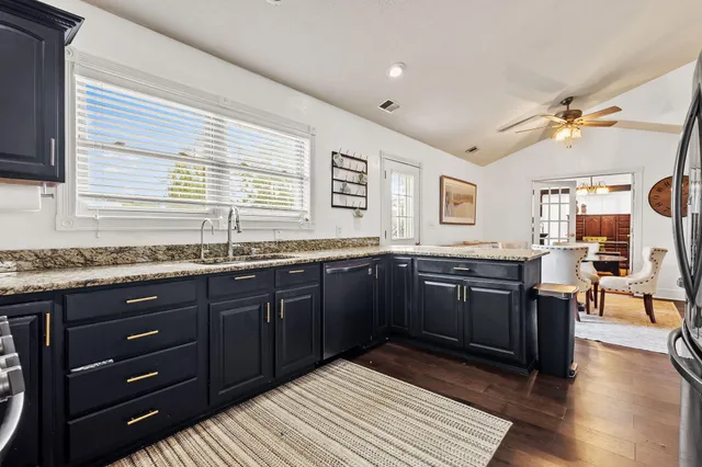 a kitchen with granite countertop a sink cabinets and wooden floor