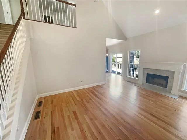 a view of an empty room with wooden floor and a fireplace