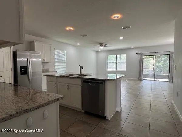 a kitchen with granite countertop a sink a counter top space appliances and cabinets