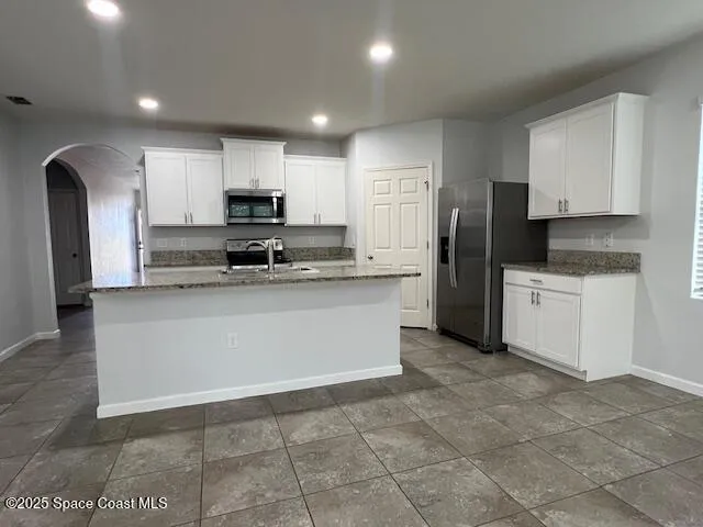 a kitchen with stainless steel appliances granite countertop a refrigerator sink and white cabinets