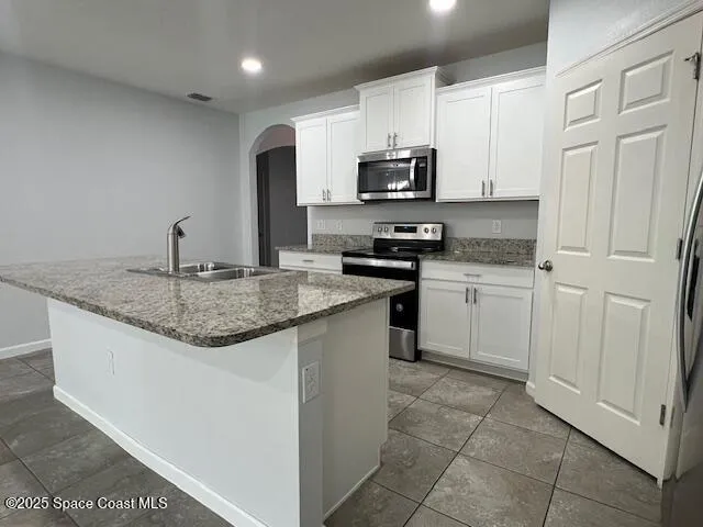 a kitchen with stainless steel appliances granite countertop a sink stove and microwave