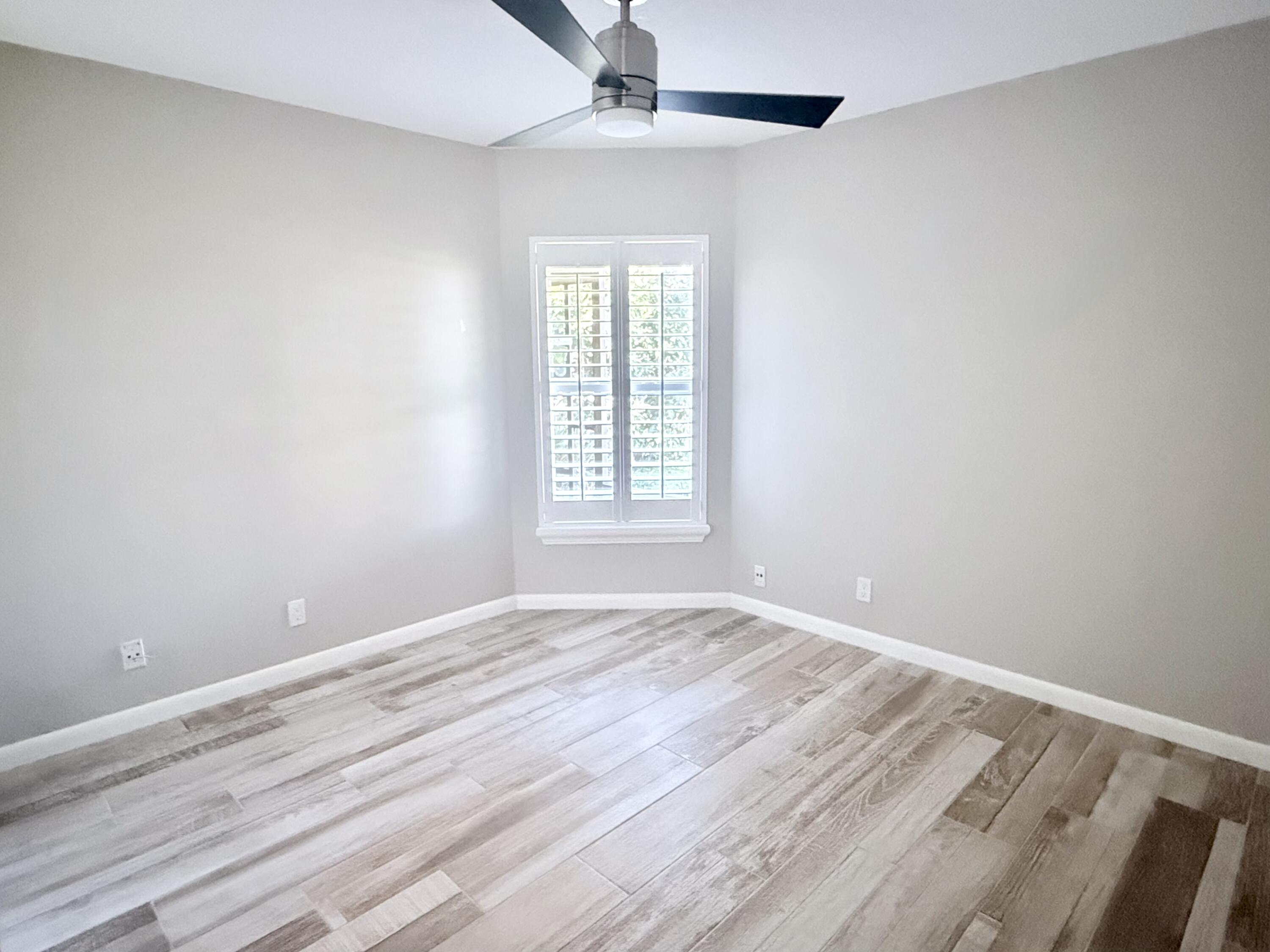 82 Sandpiper Way Boynton Beach, FL 33436 - Photo 16 of 24 a view of an empty room with wooden floor and a window