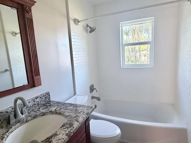 a bathroom with a granite countertop sink toilet and shower