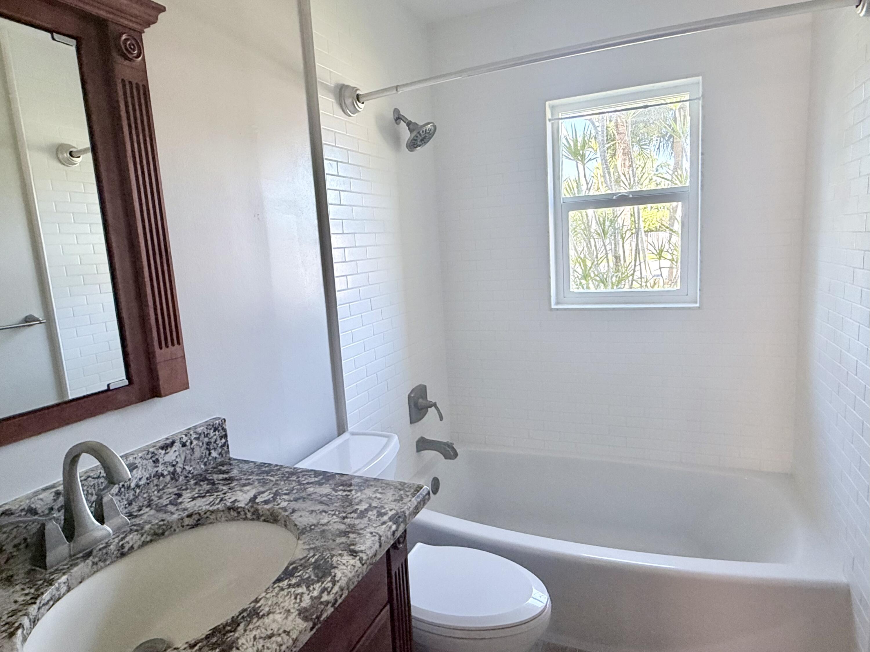 82 Sandpiper Way Boynton Beach, FL 33436 - Photo 19 of 24 a bathroom with a granite countertop sink toilet and shower