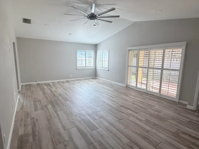 a view of an empty room with wooden floor and a window