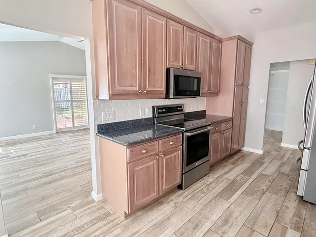 a kitchen with granite countertop a stove and a microwave