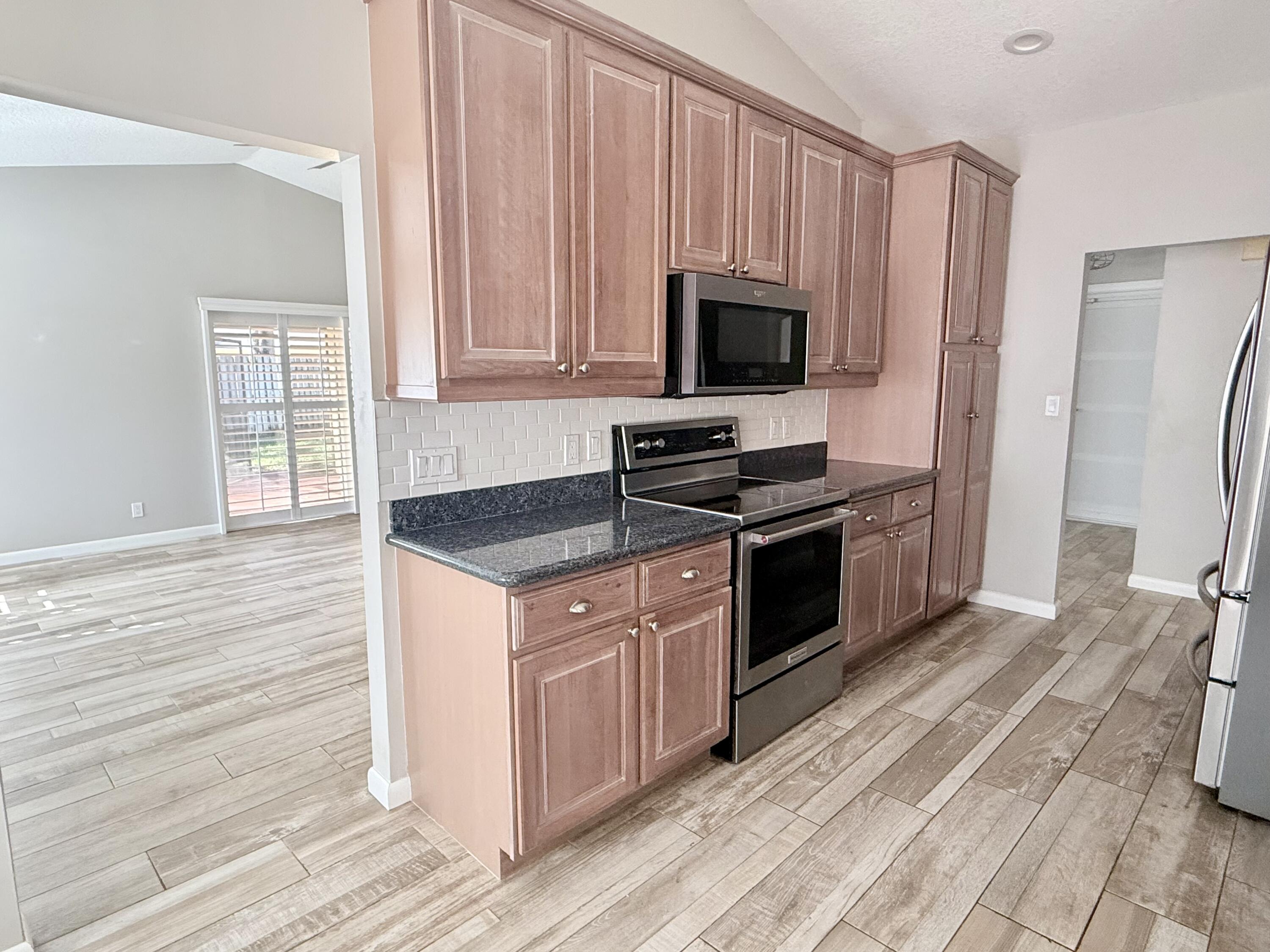 82 Sandpiper Way Boynton Beach, FL 33436 - Photo 4 of 24 a kitchen with granite countertop a stove and a microwave