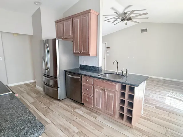 a kitchen with stainless steel appliances a sink cabinets and wooden floor