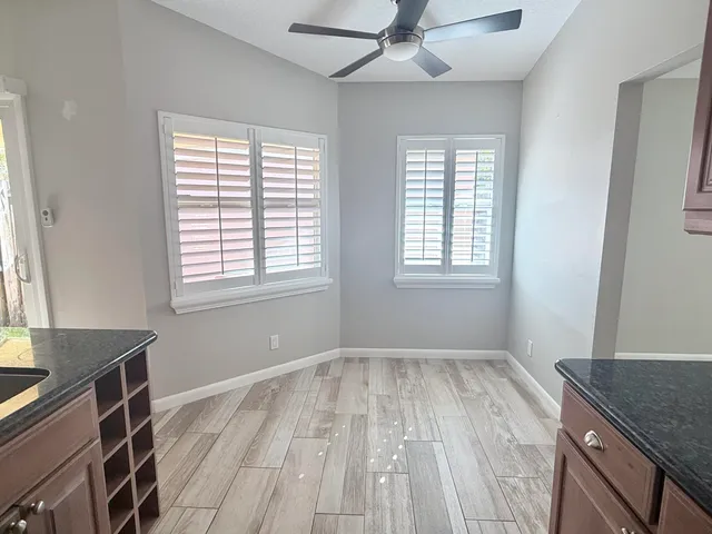 a view of empty room with wooden floor and fan