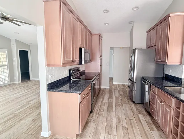a kitchen with granite countertop a sink stove and refrigerator