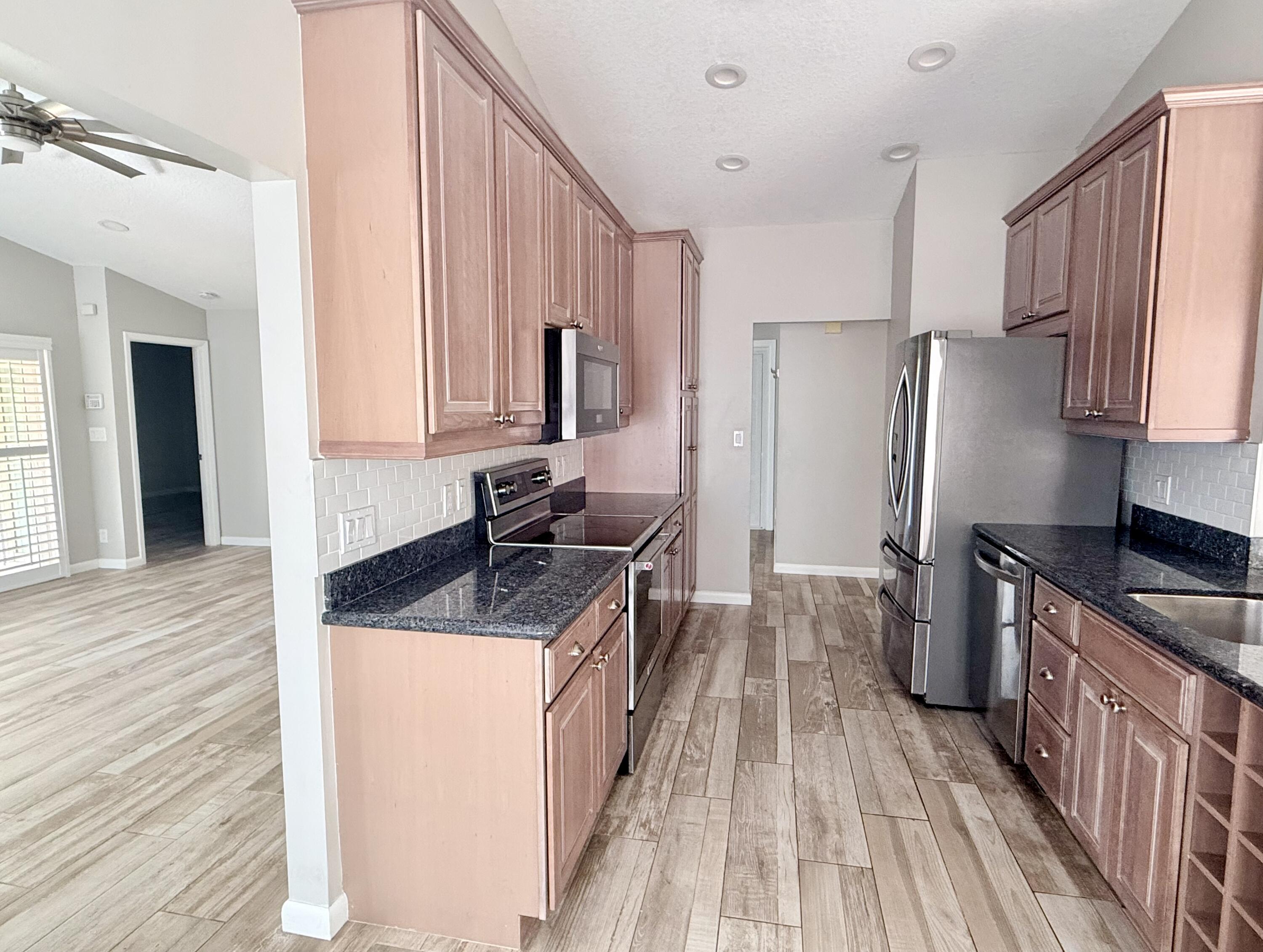 82 Sandpiper Way Boynton Beach, FL 33436 - Photo 8 of 24 a kitchen with granite countertop a sink stove and refrigerator