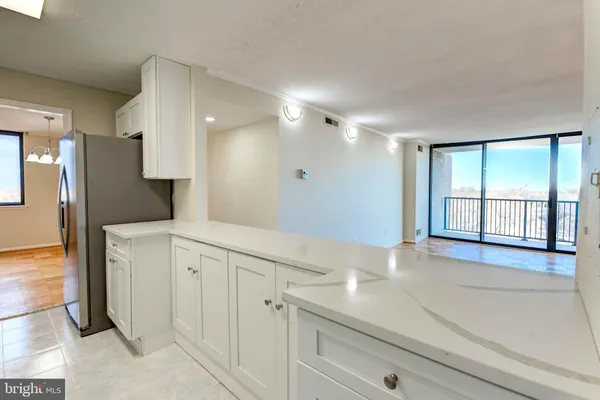 a view of a kitchen with white cabinets and a refrigerator