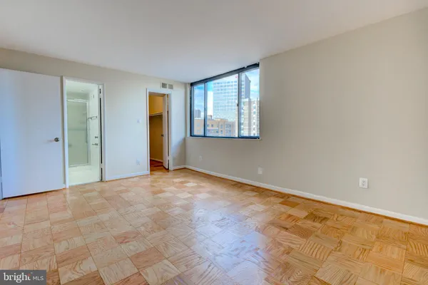 a view of an empty room with window and wooden floor
