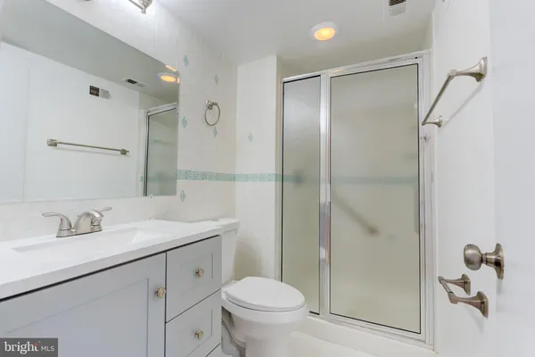 a bathroom with a shower sink vanity mirror and toilet