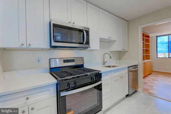a kitchen with granite countertop white cabinets and stainless steel appliances